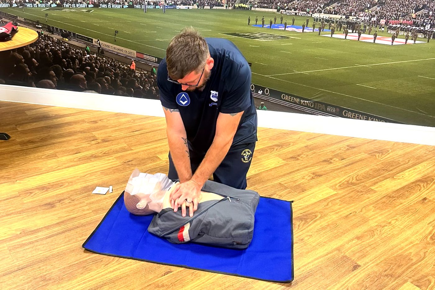 Rugby club member practising CPR on a manikin