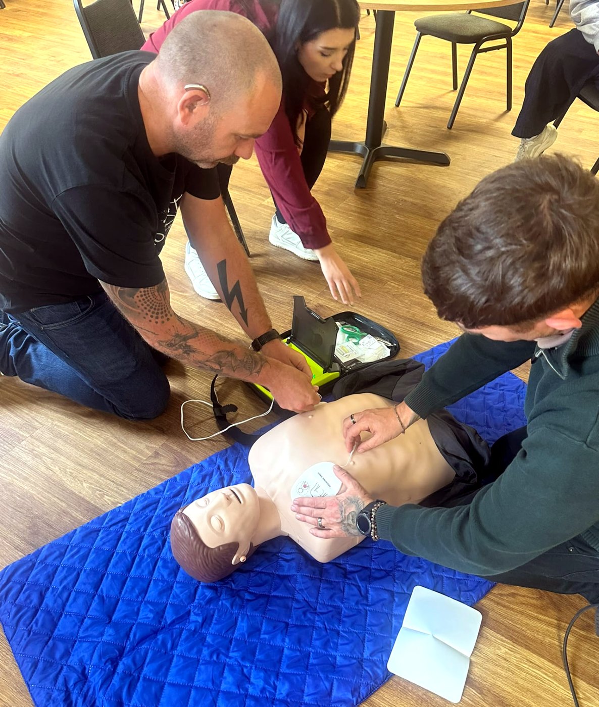 Learners working together to attach AED pads to a manikin